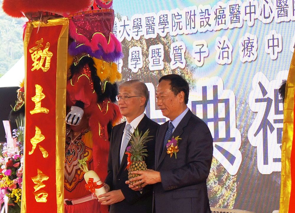 President Yang and Foxconn Chairperson Guo holding a radish and pineapple as symbols of auspiciousness