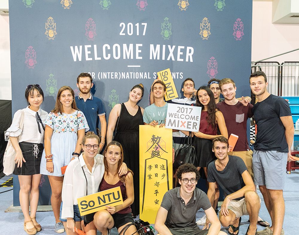 Students take a photo in front of the backdrop of the Mixer.