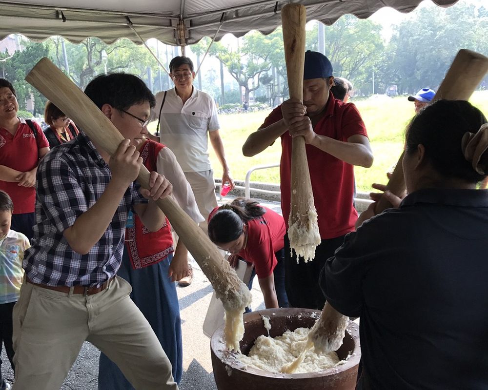 Guests and Saisiyat tribe members pound sticky rice together.