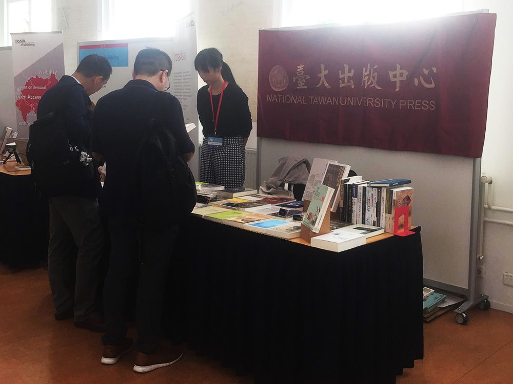 A staff member of NTU Press greets participating scholars at the exhibition stand.