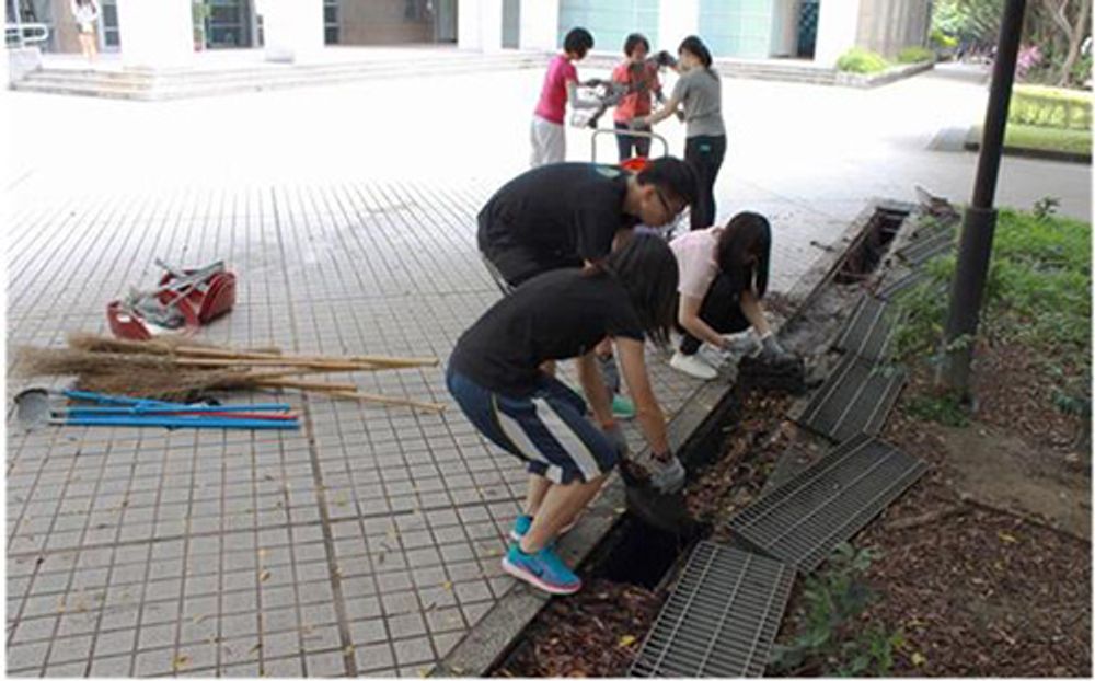 圖五、公衛大樓一樓廣場的水溝清掃作業，學生們正合力抬起溝內底層網墊